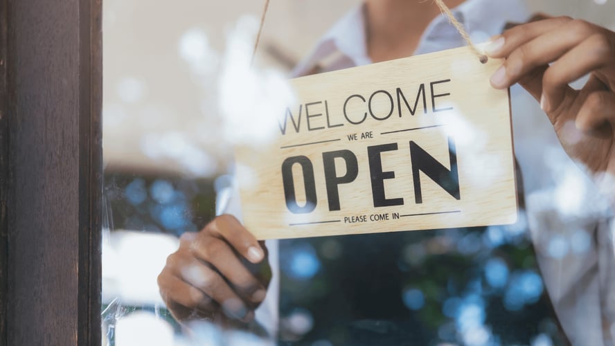 Small business owner opening their store, symbolizing the need for general liability insurance to protect against everyday risks in California operations.