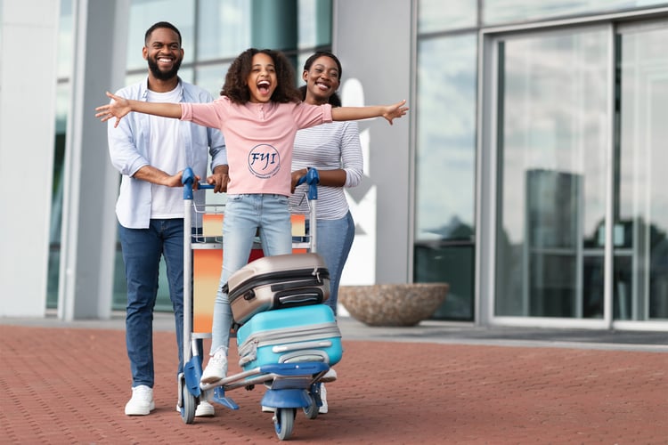 Family at airport with child on luggage cart, representing the protection and peace of mind travel insurance offers during international trips.