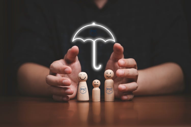 Hands shielding a smiling wooden family under a glowing umbrella labeled FYInsurance Solutions, symbolizing protection through different types of life insurance coverage.